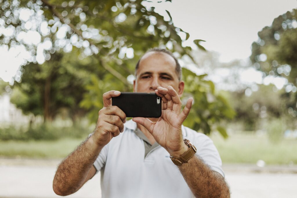 pexels-photo-1867023-1867023 Adult man using smartphone to take a photo in a natural setting, showcasing modern technology and leisure.
